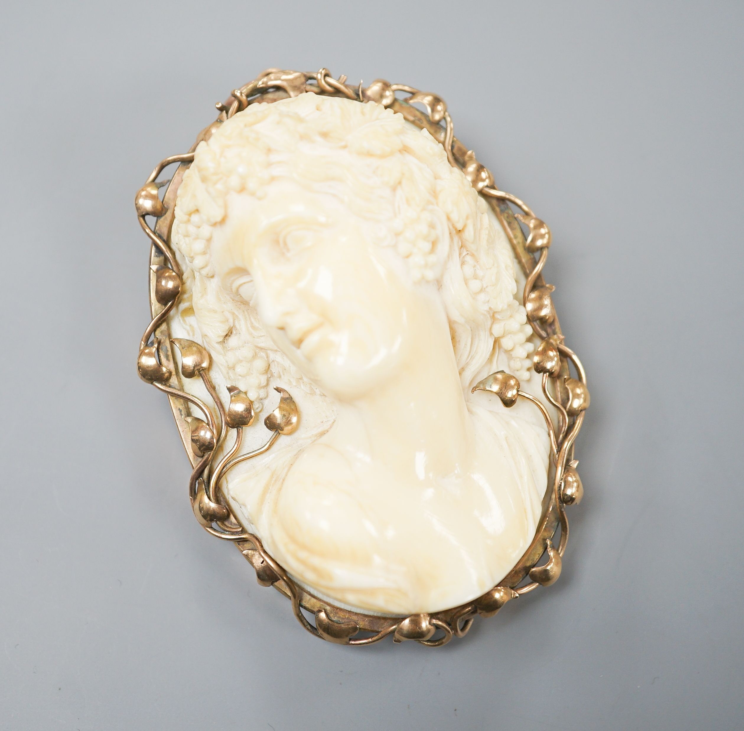 An early 20th century yellow metal mounted oval ivory cameo pendant brooch, carved with the bust of a lady, 68mm, gross weight 70 grams.